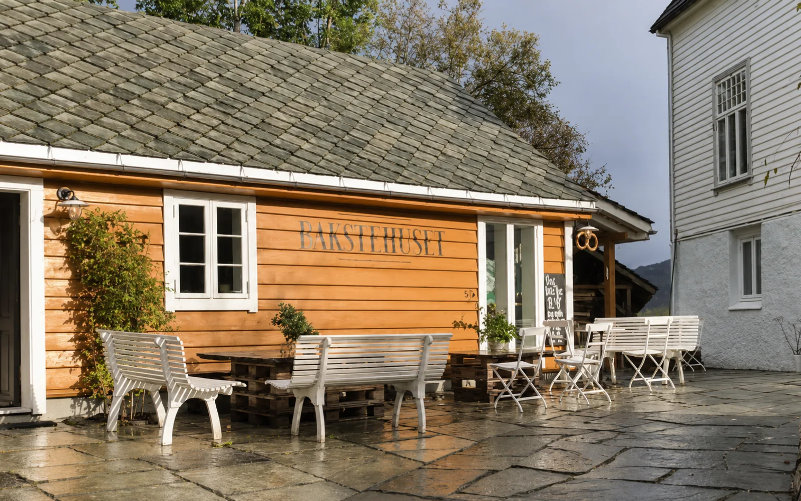 The ochre timber bakery with a slate roof and benches in the yard outside