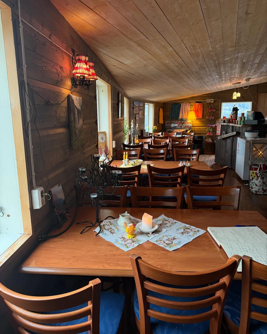 Inside the café: timber walls and ceiling, wooden tables laid with candles and cloths