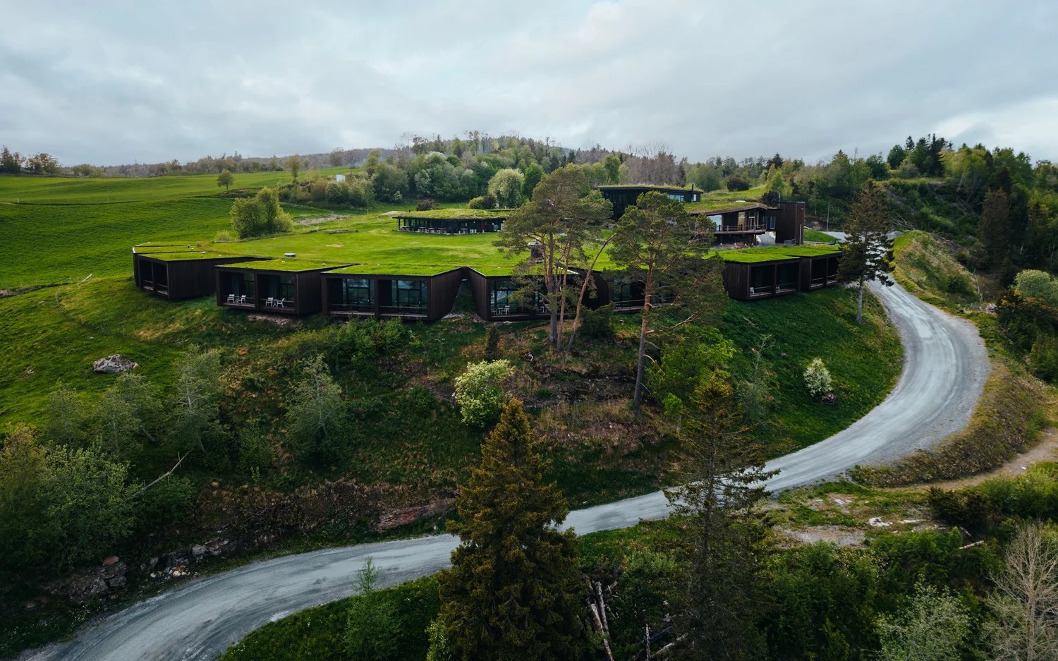Øyna Kulturlandskapshotell built into the hillside, eighteen turf roofs level with the fields